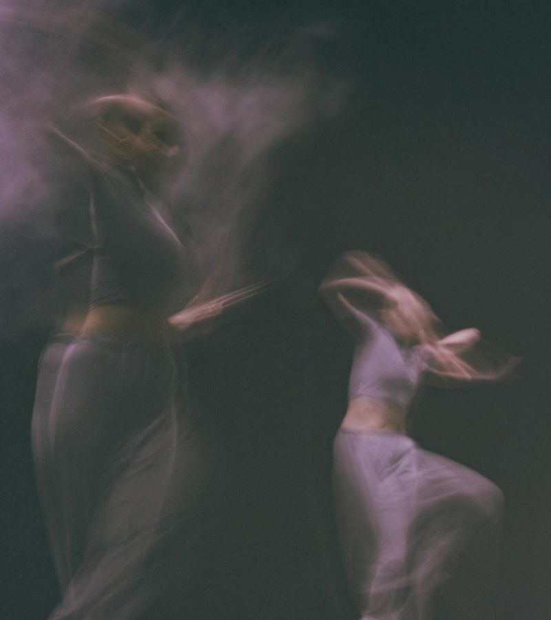 Woman performing a fluid cardio movement in a minimalist dark studio.